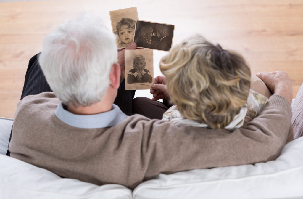 Senior couple going over old pictures of family while cuddling on sofa